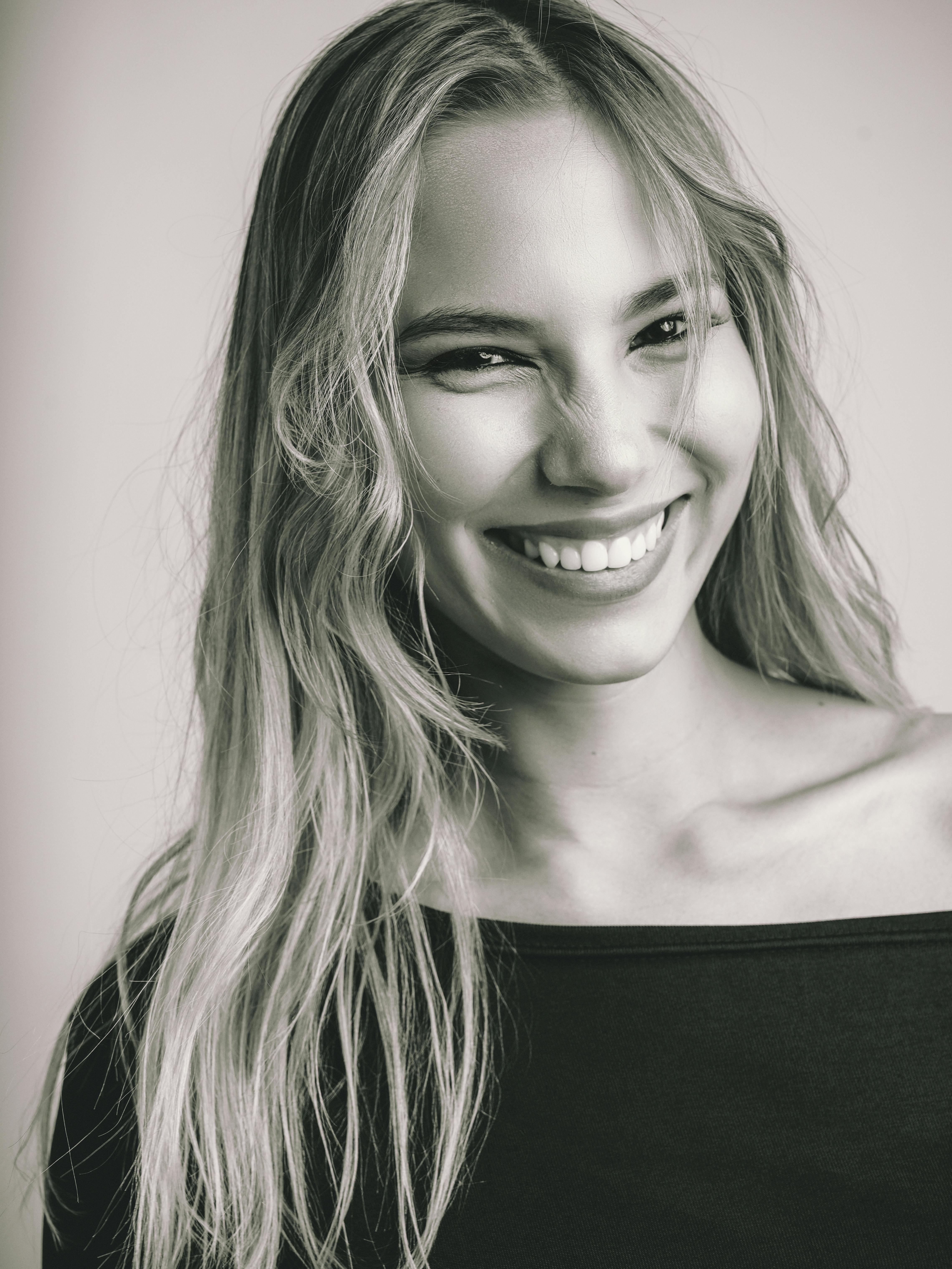 Close-up black and white portrait of a smiling young woman with long hair.