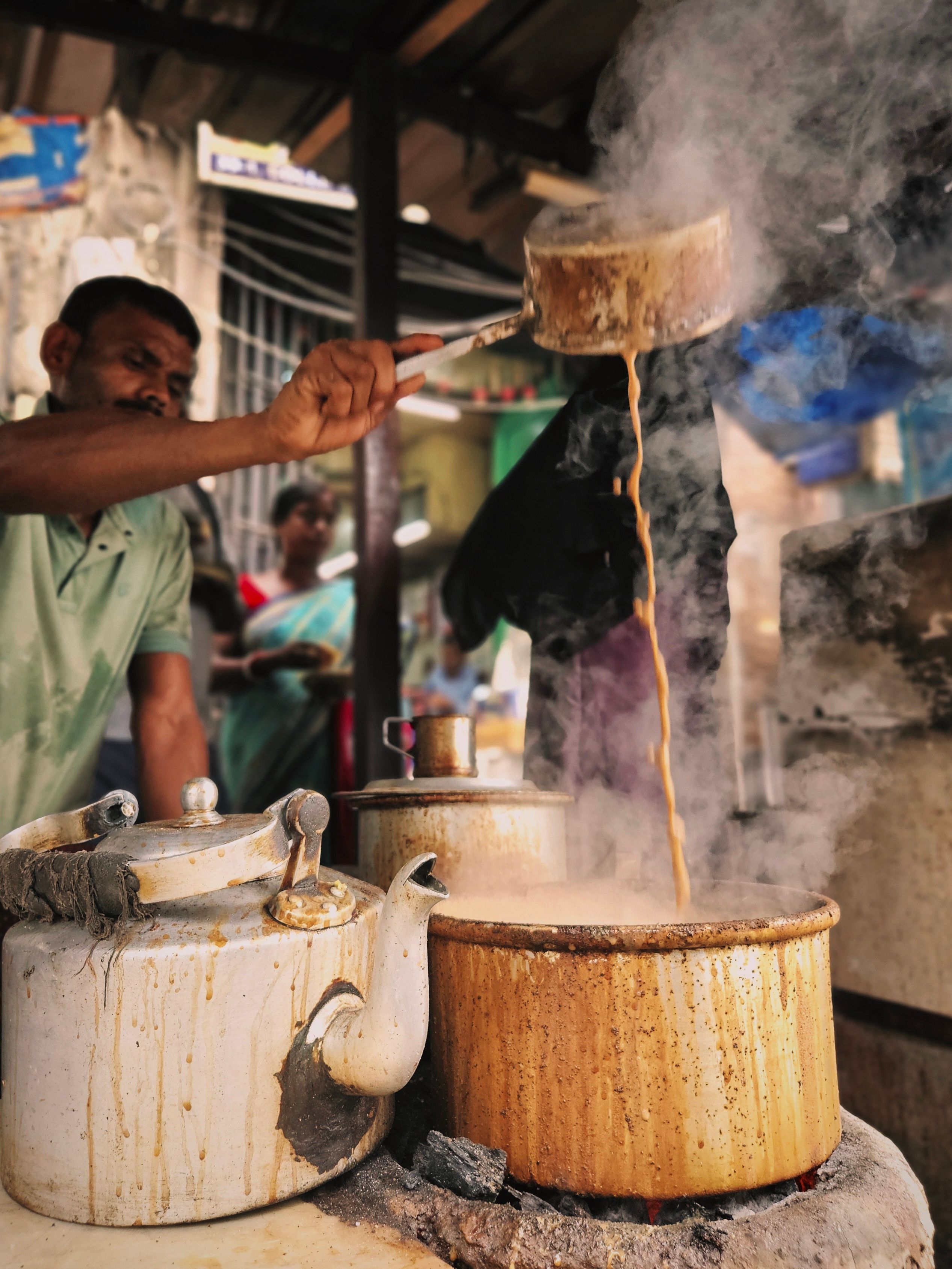 Capturing an Indian street vendor expertly preparing chai with steamy pots and vibrant background.