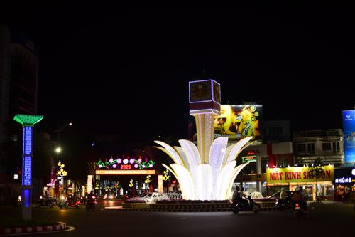 Free A vibrant illuminated fountain in an urban cityscape at night with busy street traffic and neon signs. Stock Photo