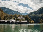 德国巴伐利亚州国王湖上，坐落着风景如画的船屋，四周环绕着郁郁葱葱的山脉