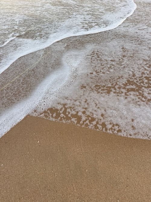 Free Soft waves gently touch the sandy beach, creating a peaceful shore scene. Stock Photo