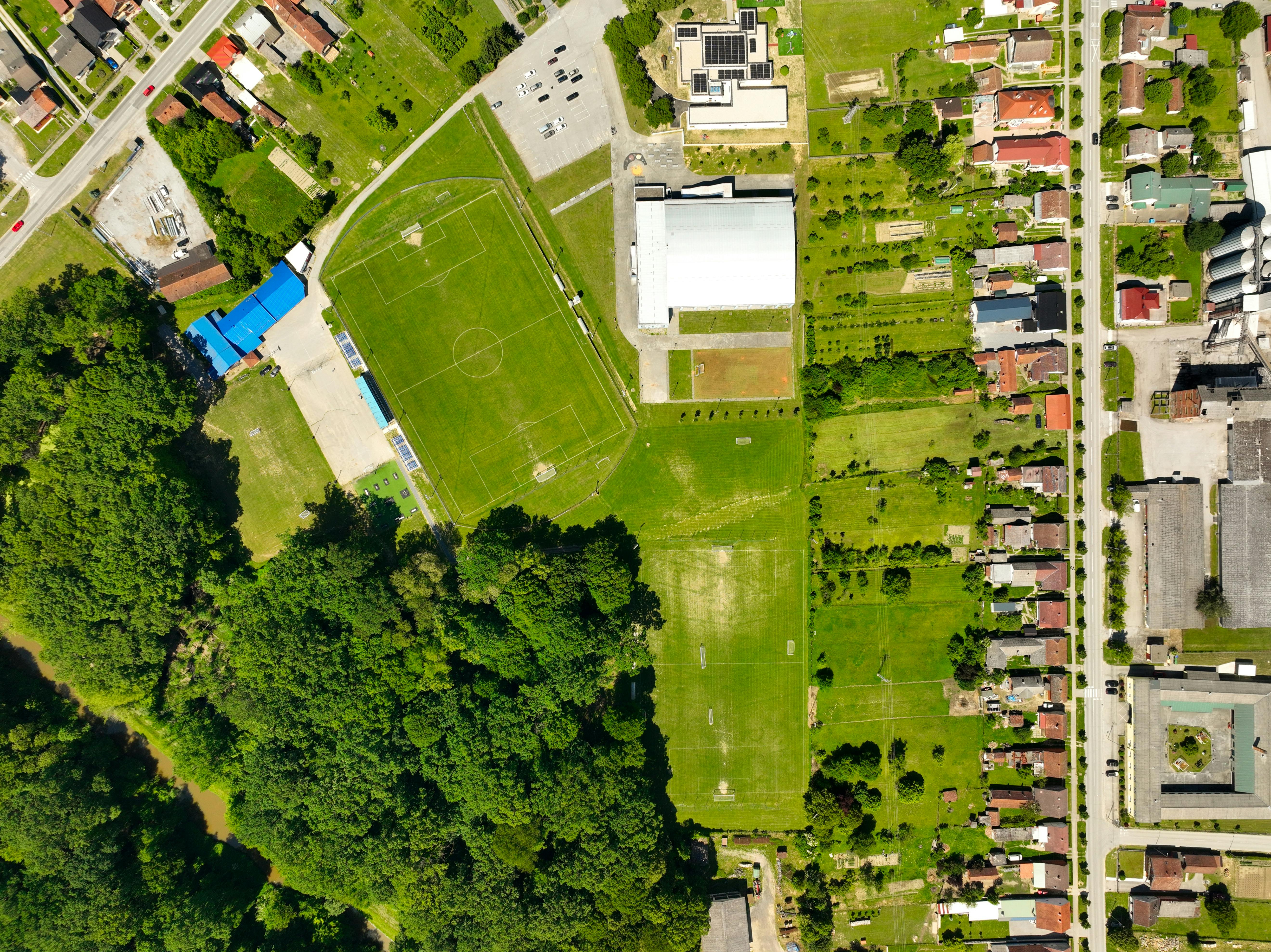 Aerial shot of a sports complex with lush greenery and residential area in Garešnica, Croatia.