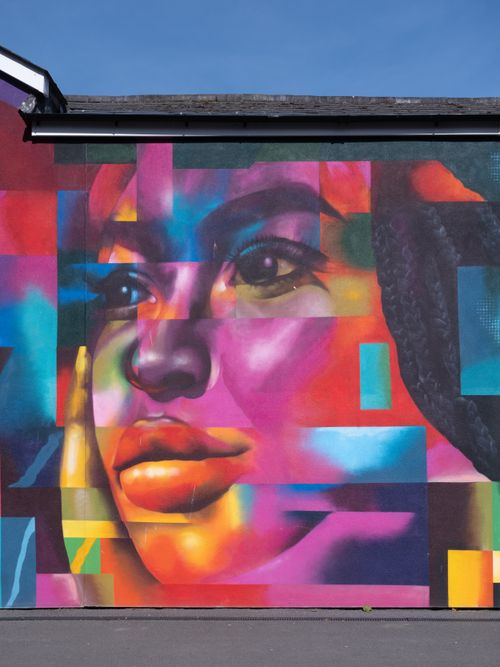 Free Colorful street art mural depicting a woman's face on a building wall. Stock Photo