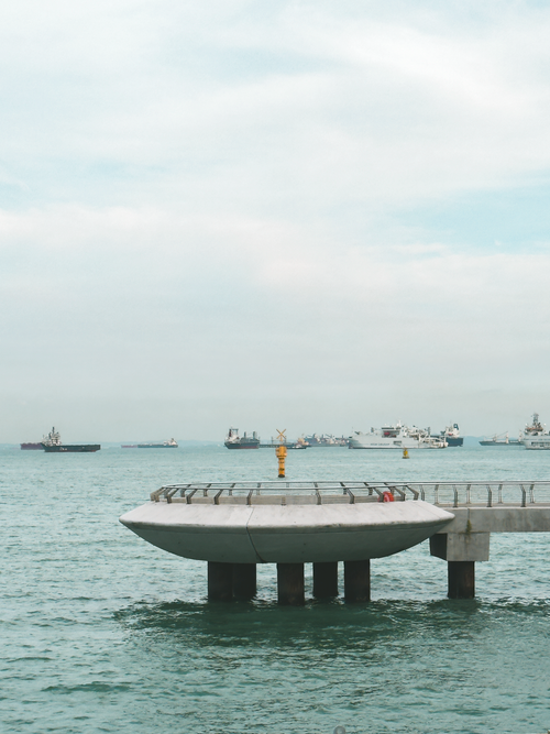 Free Peaceful ocean scene with a pier and distant ships under a cloudy sky. Stock Photo