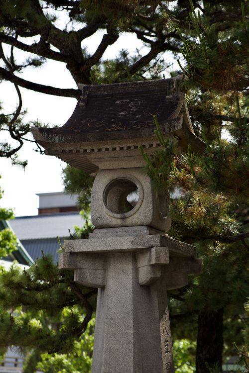 Free A serene Japanese stone lantern surrounded by lush greenery in an outdoor garden setting. Stock Photo