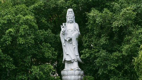Free Serene statue of Guan Yin amidst lush greenery, symbolizing peace and compassion. Stock Photo