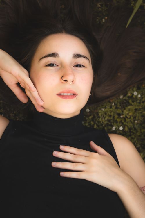 Free A serene portrait of a young woman lying on grass during the day, showcasing relaxation and tranquility. Stock Photo