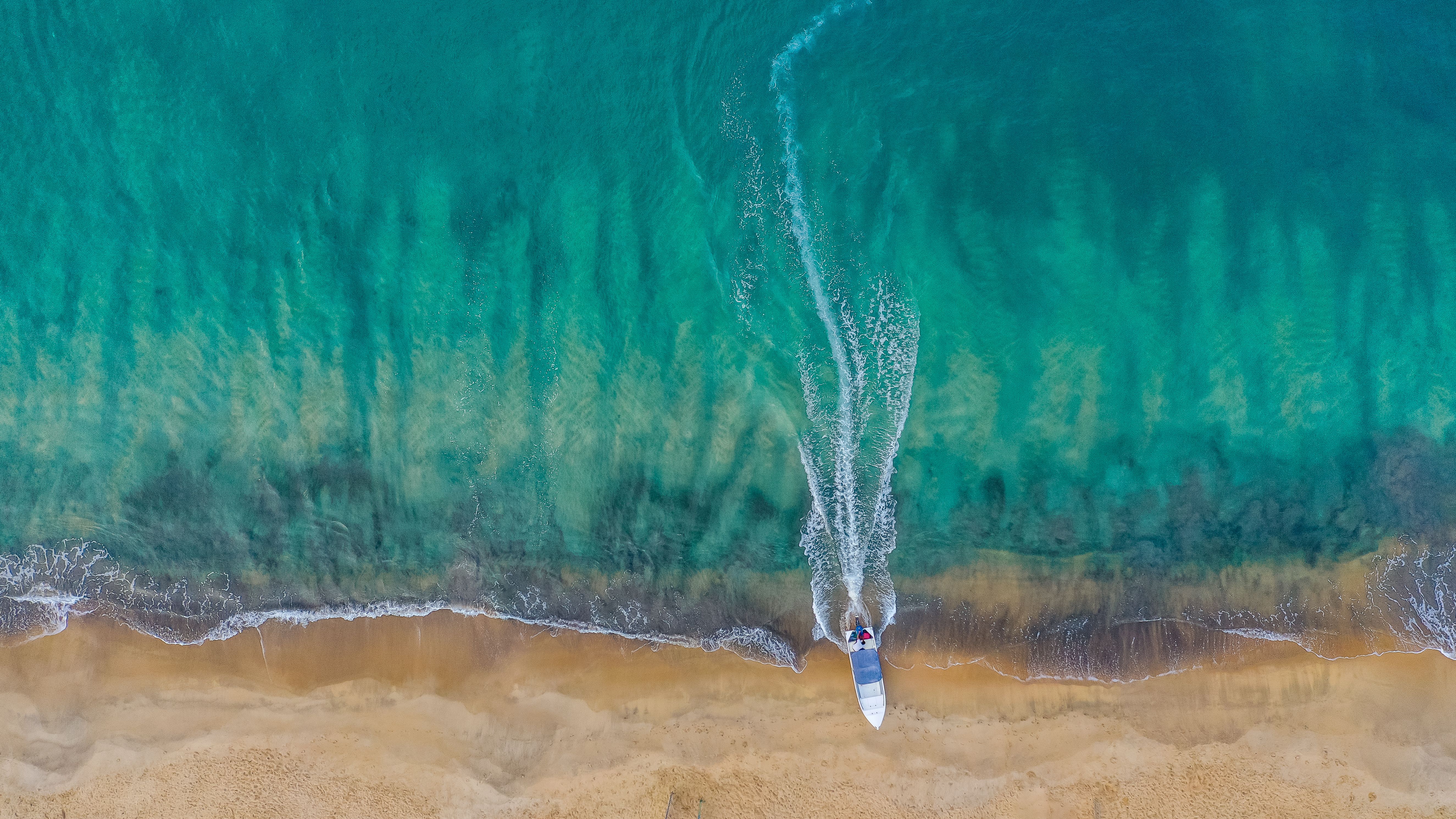 A single boat anchored off a tropical coastline in clear blue water