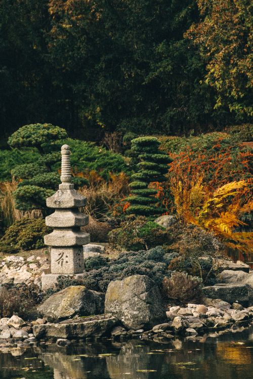 Free Tranquil Japanese garden with stone pagoda surrounded by lush greenery in Wrocław, Poland. Stock Photo