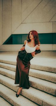 Woman in stylish outfit leaning on urban steps, showcasing modern fashion.