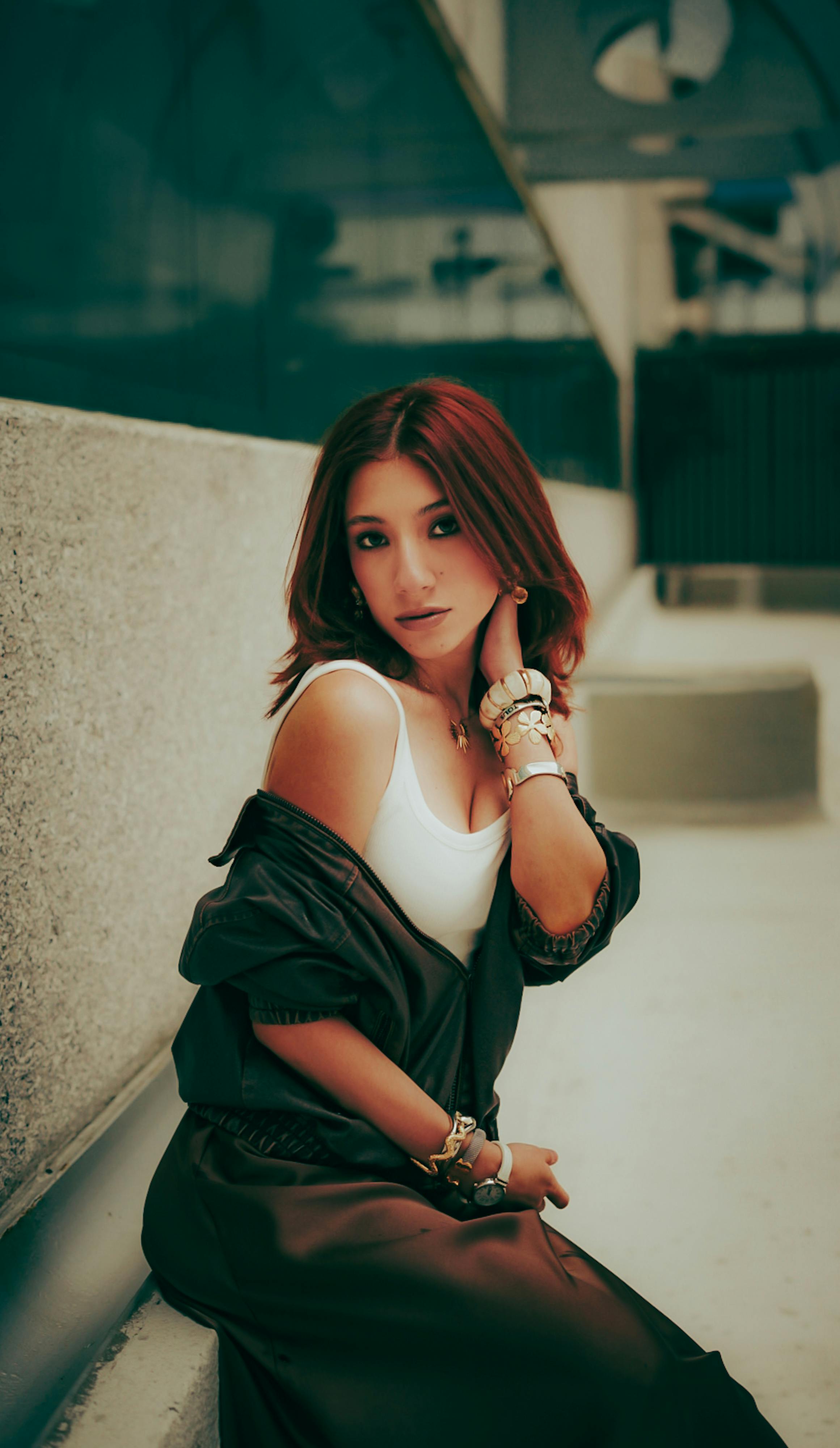 Stylish woman poses outdoors in a city environment, showcasing fashion and accessories for urban lifestyle.