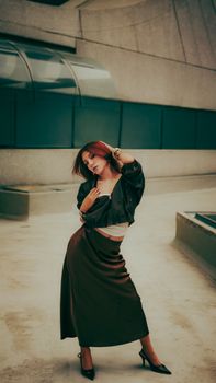 Fashionable woman posing in sleek modern architectural setting, exuding confidence and style.