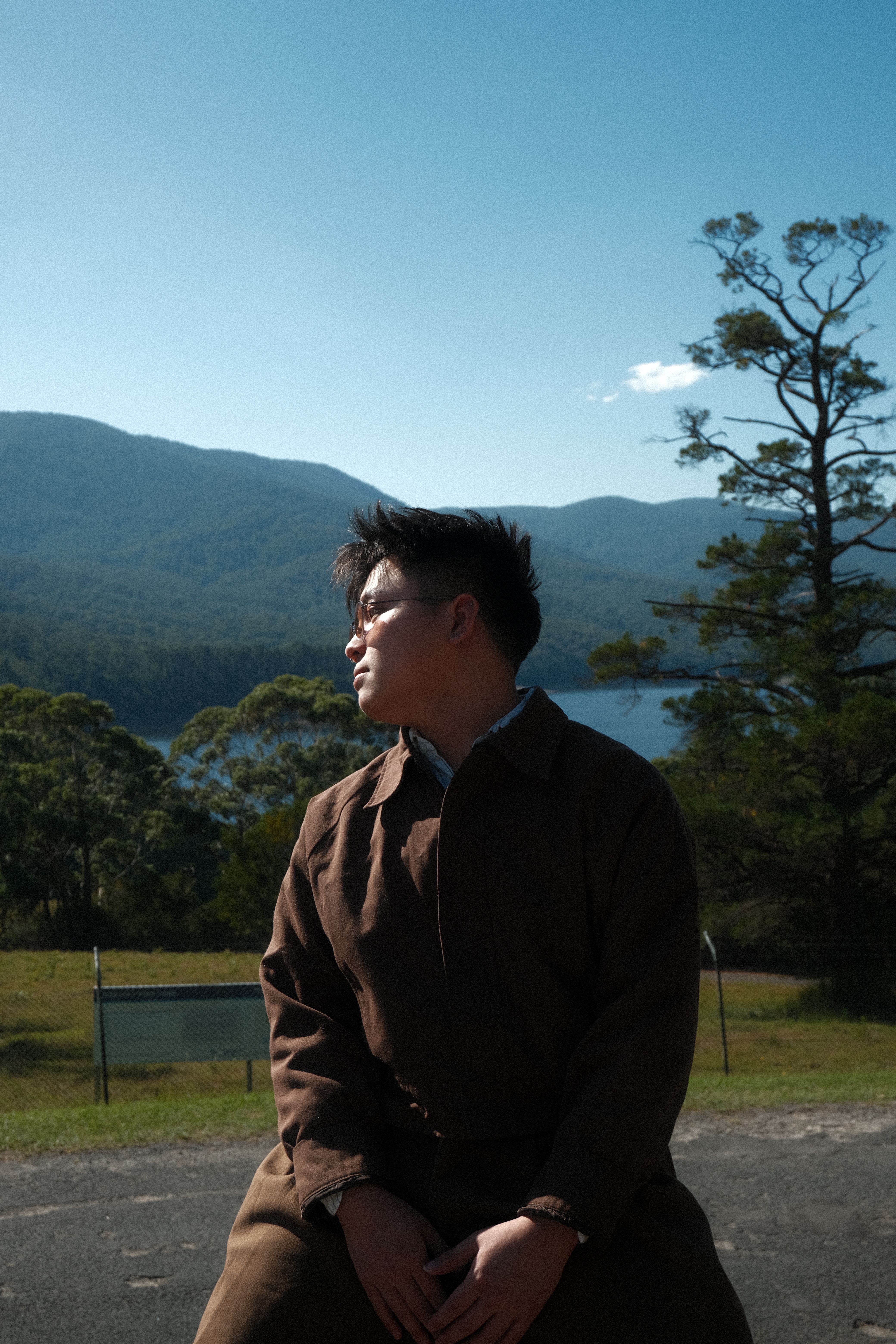 Young man outdoors with vast mountain view and serene ambiance, soaking in nature's beauty.