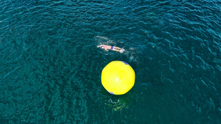 Man Swimming Around Inflated Buoy