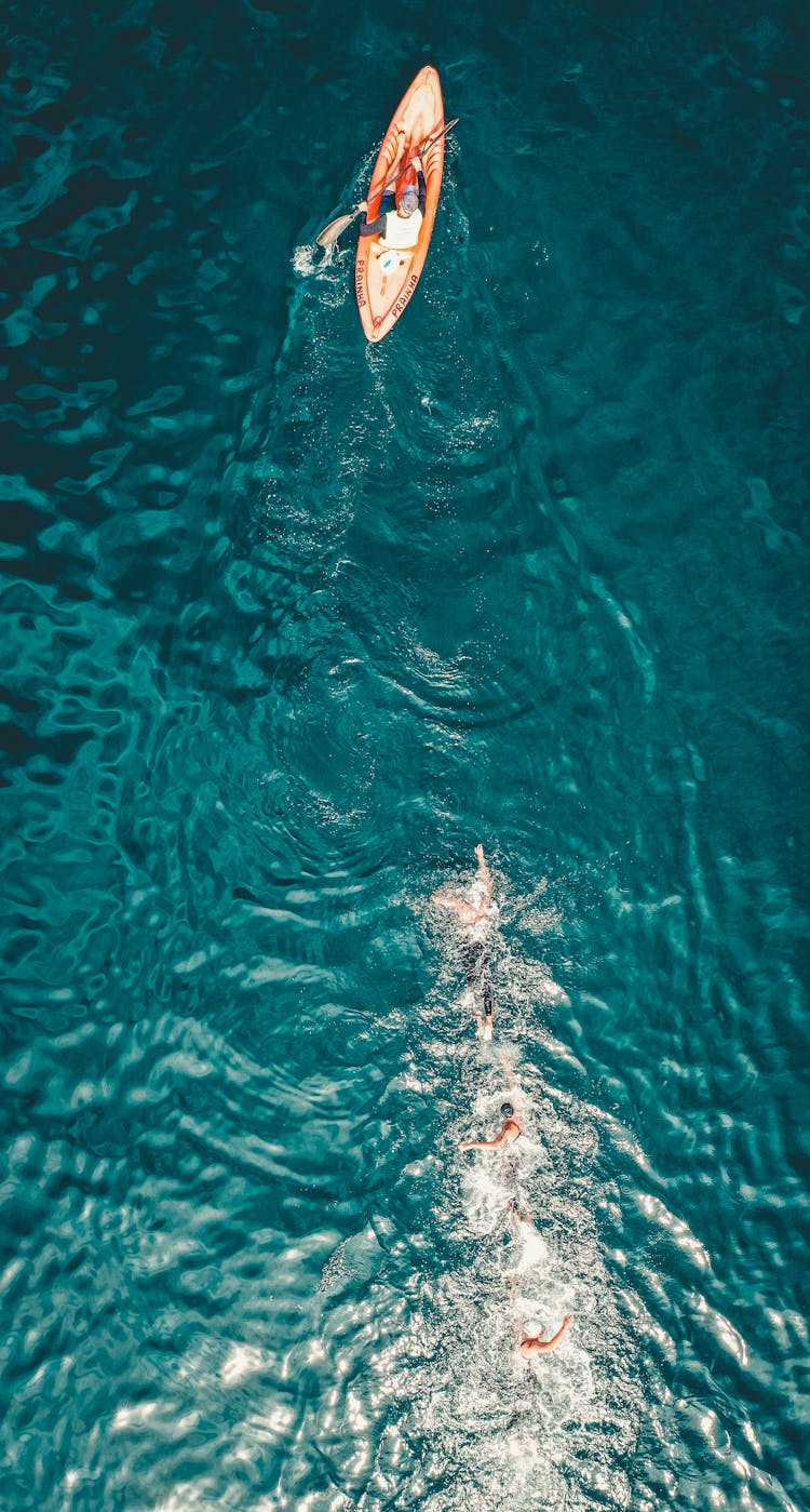 People Swimming After Boat In Sea Water