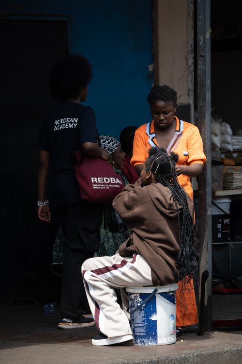 Free Outdoor scene of women braiding hair on the street in Johannesburg. Stock Photo