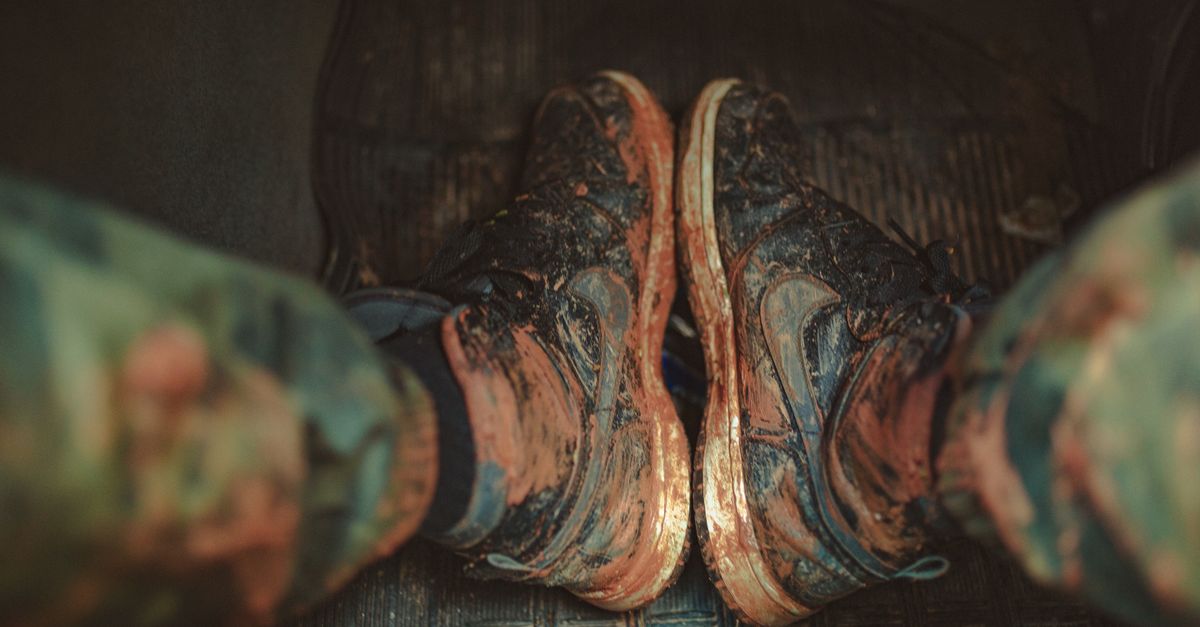Witte sneakers waarop modder voorzichtig met een zachte borstel wordt verwijderd