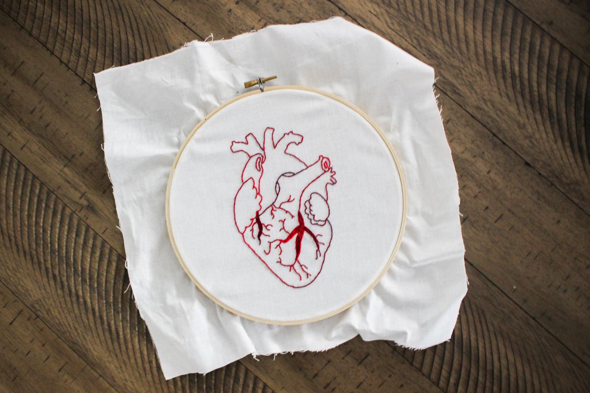 Bordir tangan motif hati merah di atas kain putih sebagai sentuhan personal untuk baju upcycle
