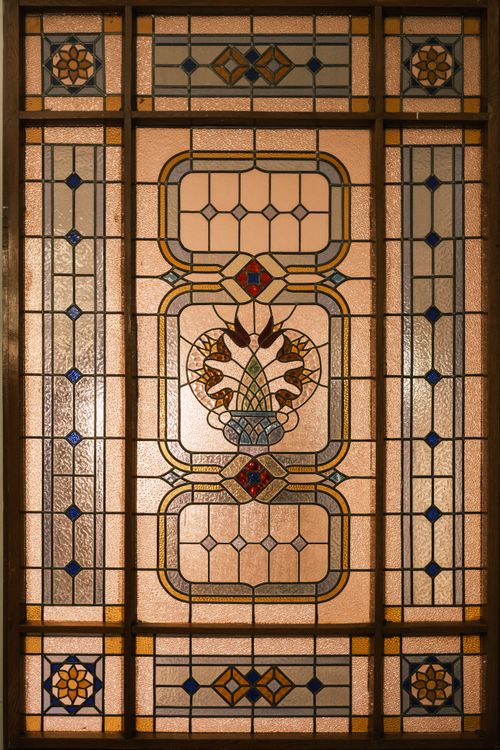 Free An elegant vintage stained glass window with an intricate geometric and floral pattern, showcasing artistry and craftsmanship. Stock Photo