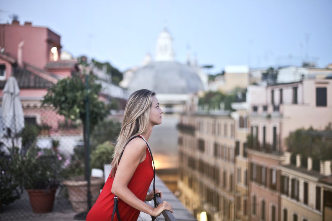 Free Woman in Red Sleeveless Dress Standing on Roof Top Stock Photo