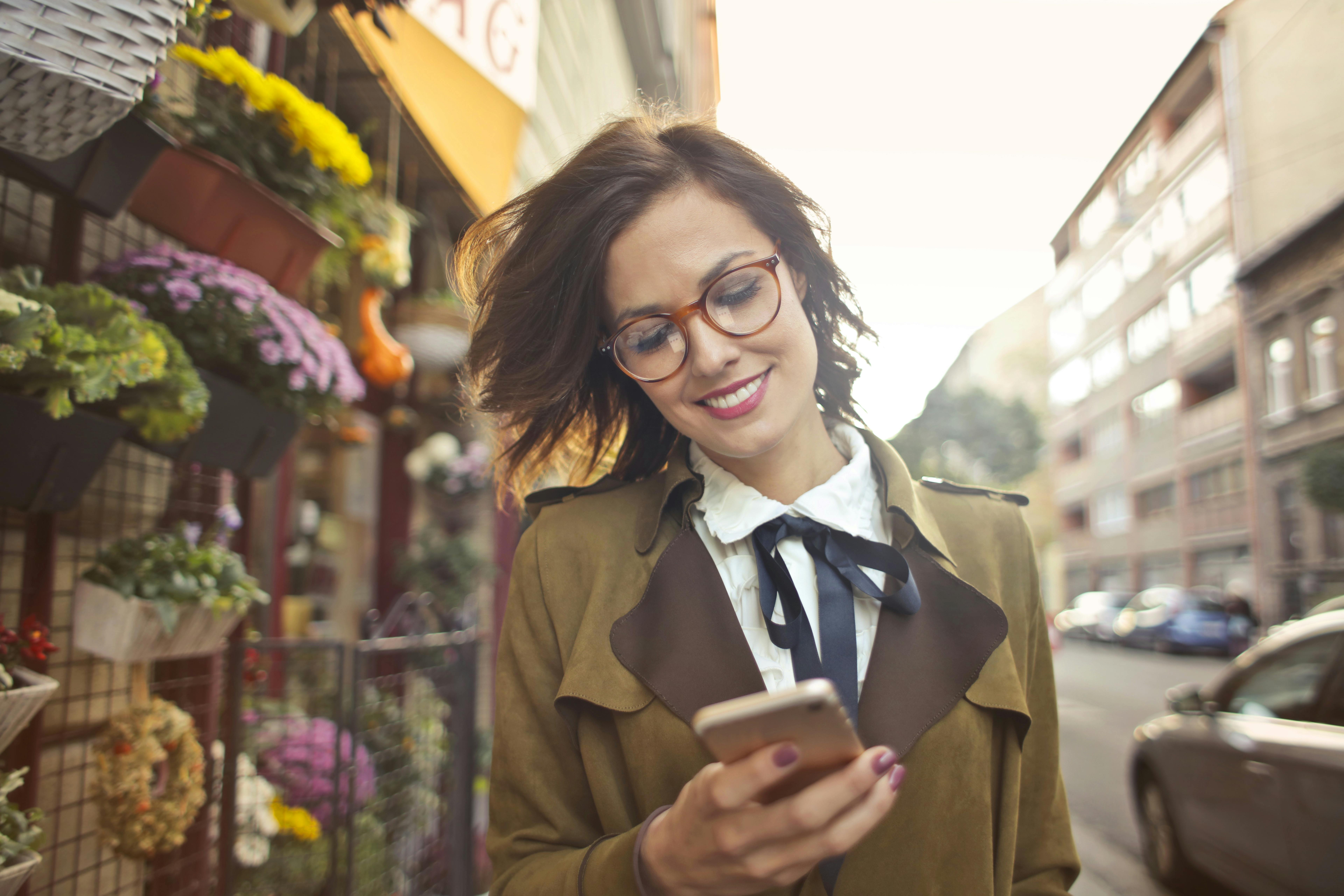 woman beside flower shop using smartphone