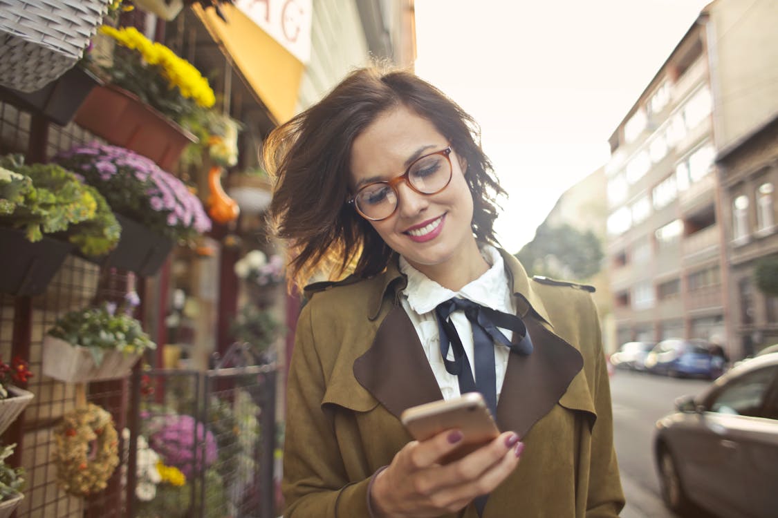 Frau neben Blumenladen mit Smartphone