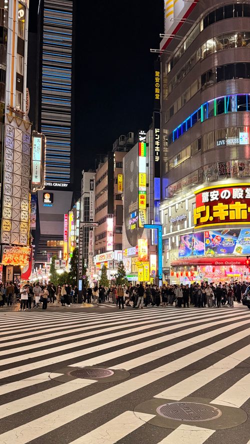 Free Lively Tokyo night scene with bustling crowds and bright neon signs in Shinjuku district. Stock Photo