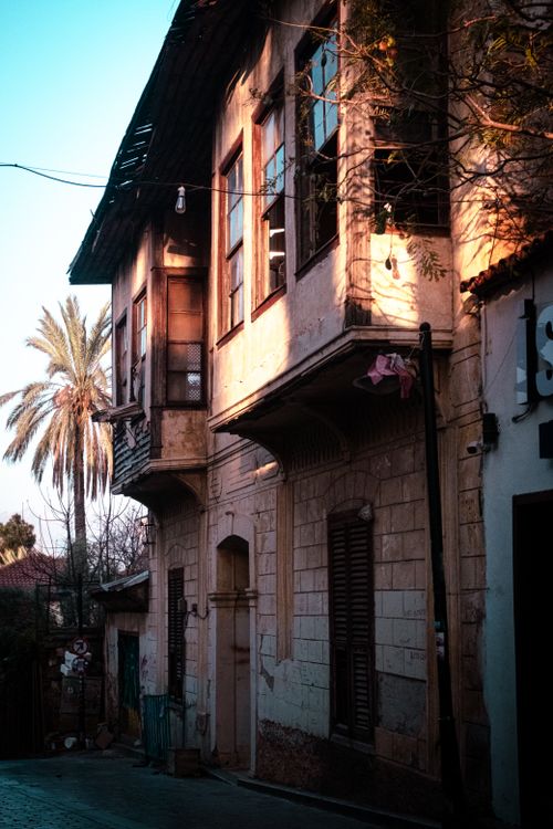 Free Historic building facade with afternoon light casting shadows, featuring traditional architecture and palm trees. Stock Photo