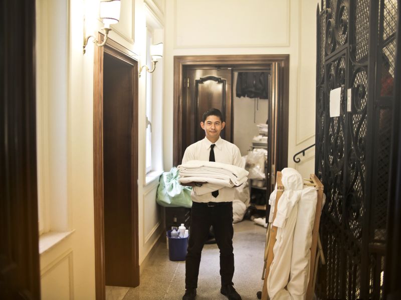 Hotel staff member carrying fresh linen in a hotel corridor