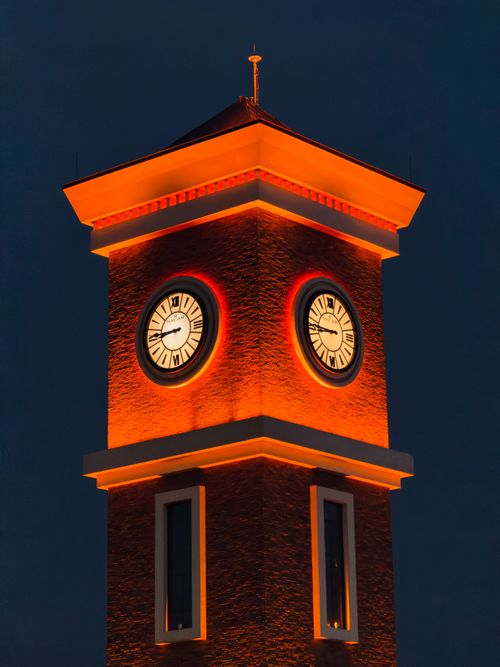 Free A beautifully illuminated clock tower glowing warmly against a night sky. Stock Photo