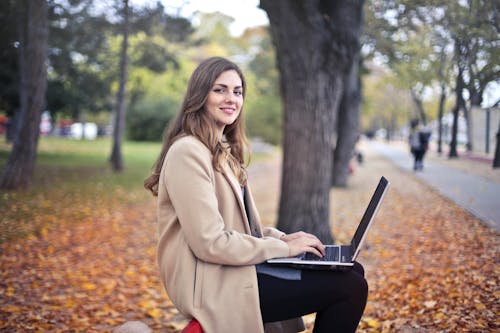 公園でネットブックを使用してうれしそうな自信を持って女性