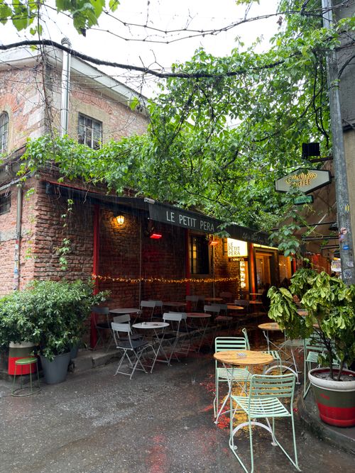Free Cozy outdoor café in İstanbul with empty tables under leafy canopy, creating an inviting atmosphere. Stock Photo