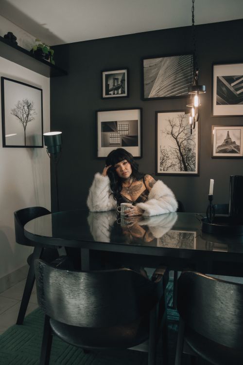 Free A stylish woman with tattoos enjoying a drink in a chic, modern dining room setting. Stock Photo