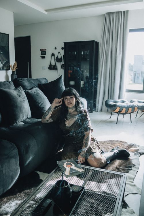 Free A tattooed woman sits in a modern living room, enjoying a calm moment surrounded by contemporary decor. Stock Photo