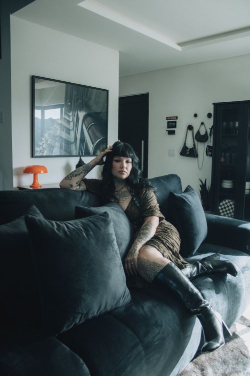 Free Contemporary portrait of a woman with tattoos relaxing on a plush sofa in a stylish living room. Stock Photo