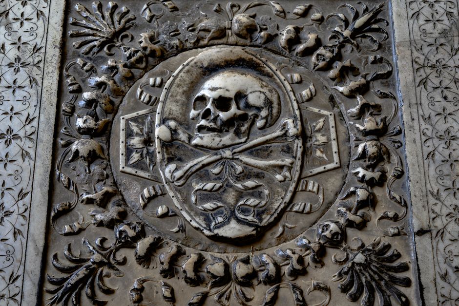 Detailed skull and crossbones carving on a historic monument in Pisa, Italy.