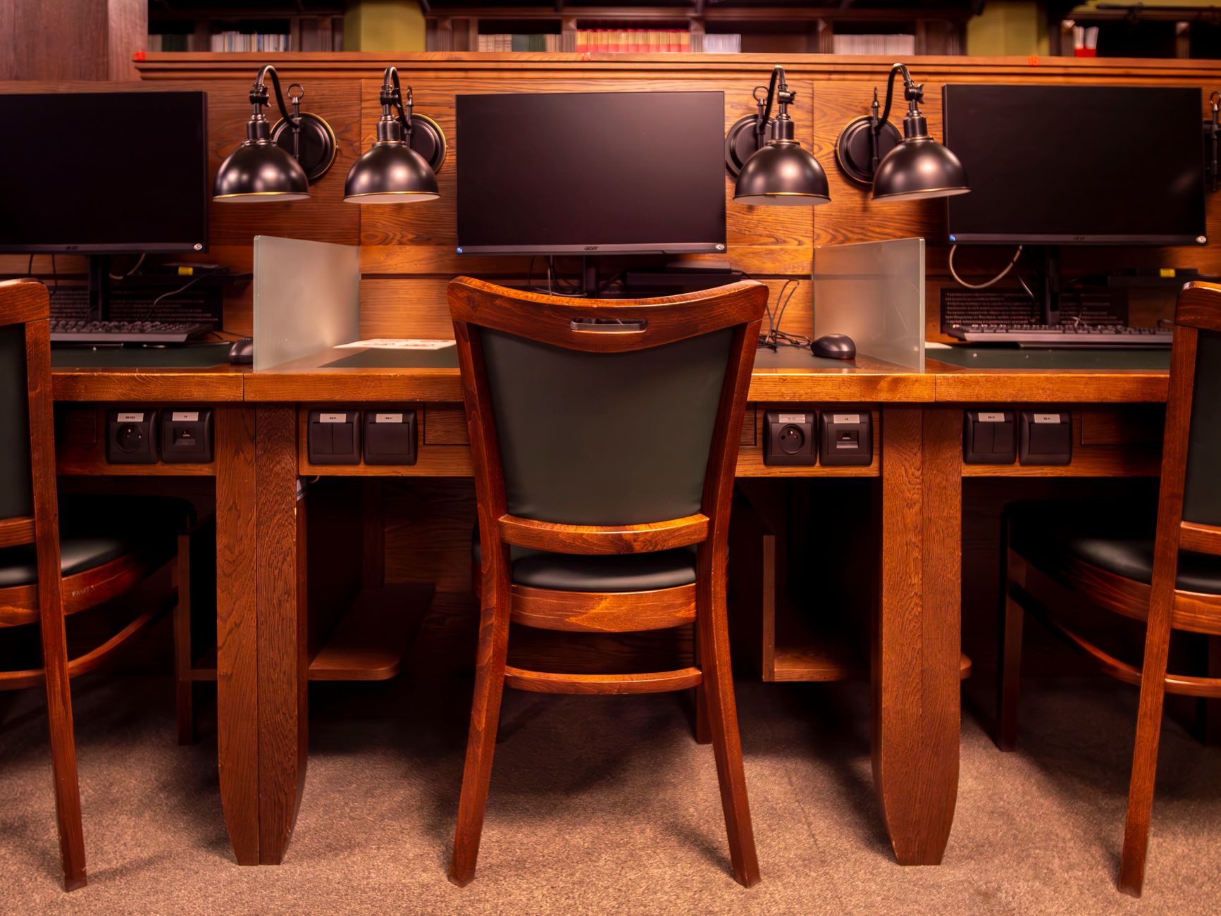 Library computer workstations in Wrocław with classic wooden design and modern computers.