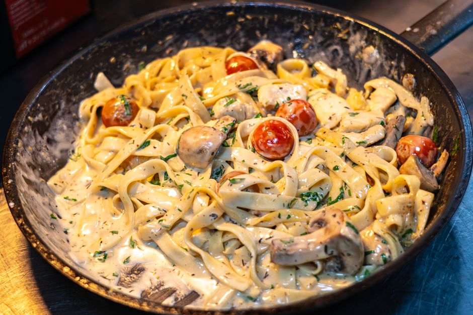 Baked chicken breasts smothered in a creamy mushroom sauce in a white baking dish, garnished with fresh thyme and grated parmesan.
