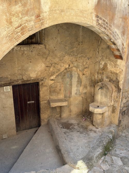 Free Rustic stone wall with an ancient fountain and door in Guimerà, Spain. Stock Photo