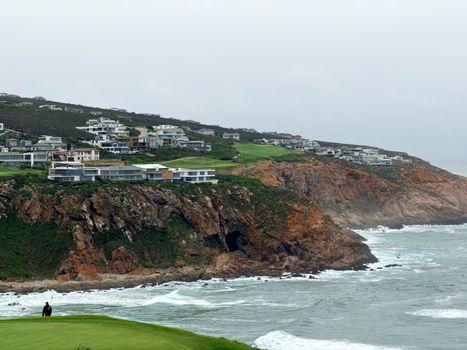 Stunning coastal view of a golf course and modern homes on cliffs in George, South Africa.