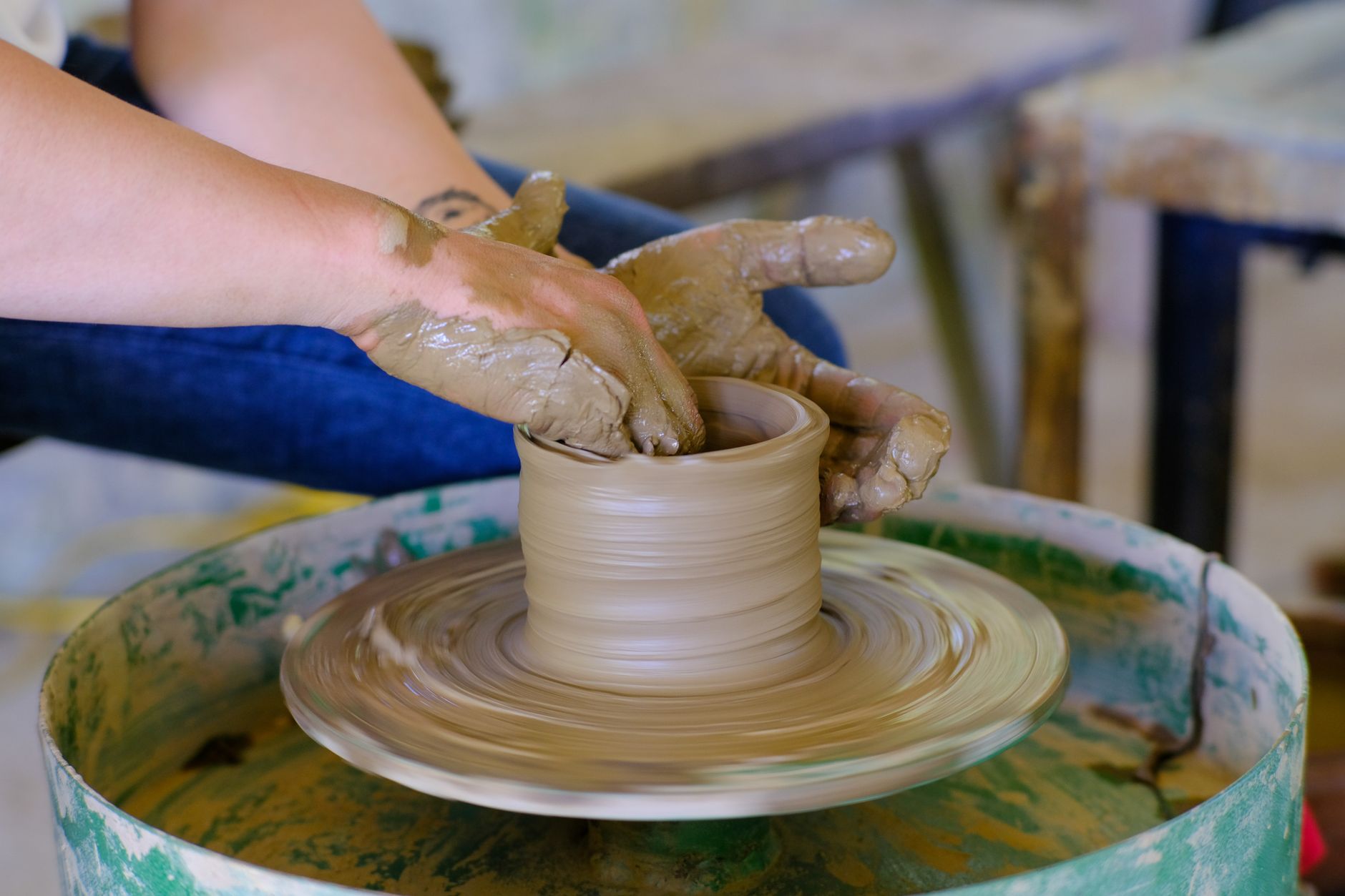 Close-up of hands of a potter molding clay on a spinning wheel, showcasing traditional craftsmanship.