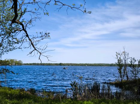 Tranquil spring view of Bay of Quinte with a small boat under the clear blue sky.