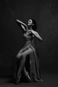 Graceful ballerina in a long dress posing artistically in a studio setting.