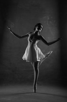 A graceful ballerina performing a classic pose in a black and white studio setting.