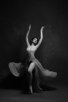 Black and white image of a ballet dancer in a flowing dress, captured in motion.
