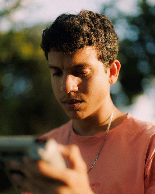 Free A young man engrossed in reading a book outdoors during golden hour. Stock Photo