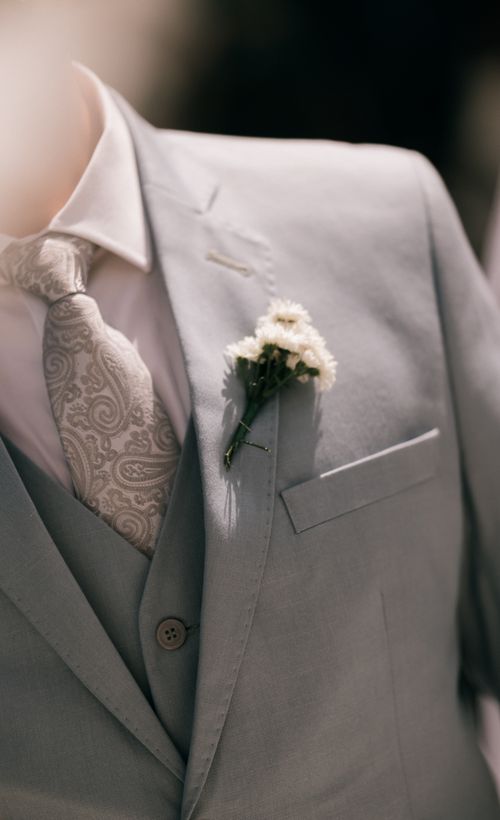 Free A detailed view of a groom's light gray suit with a paisley tie and white boutonniere, perfect for weddings. Stock Photo