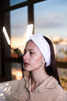 A woman with a headband in a beauty studio setting, focused on skincare.