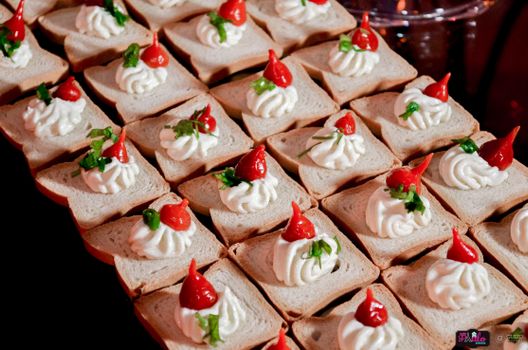 Gourmet appetizers with cream cheese and red peppers on bread slices, perfect for parties or buffets.