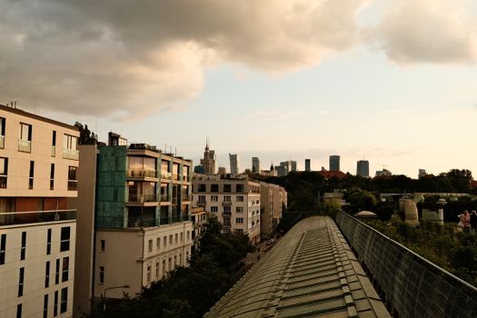 A view of a city skyline with modern buildings under a cloudy sunset.